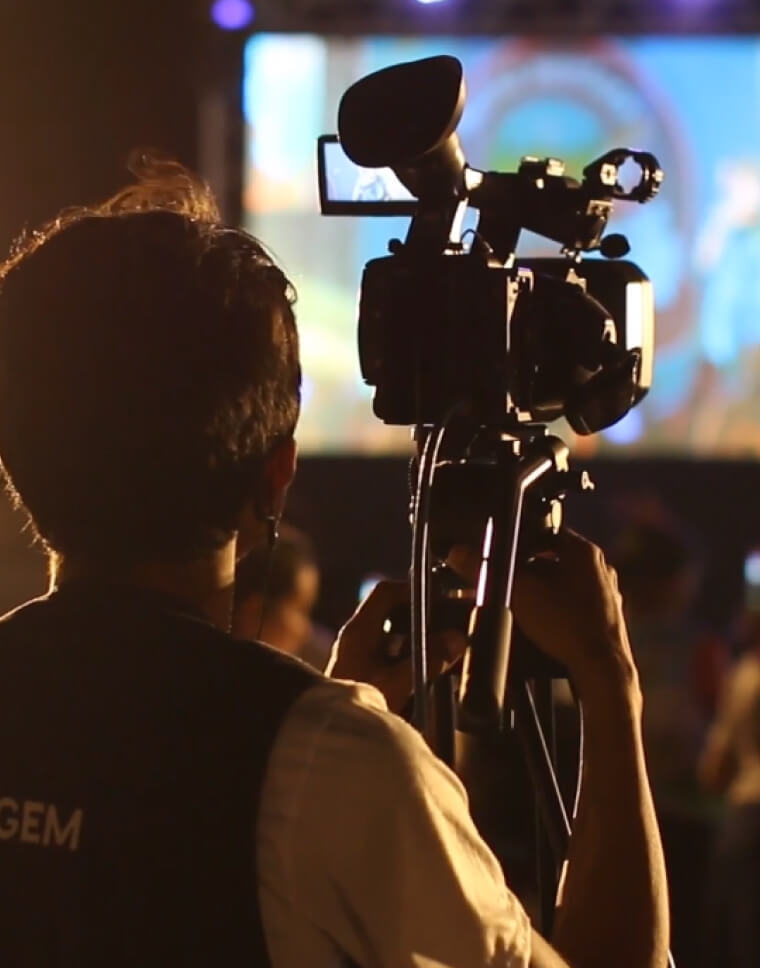 Man behind a camera filming an event